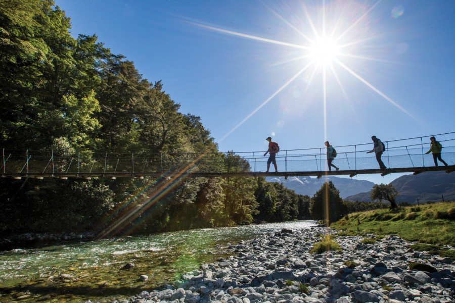 Trampers walking across riverbed on swing bridge