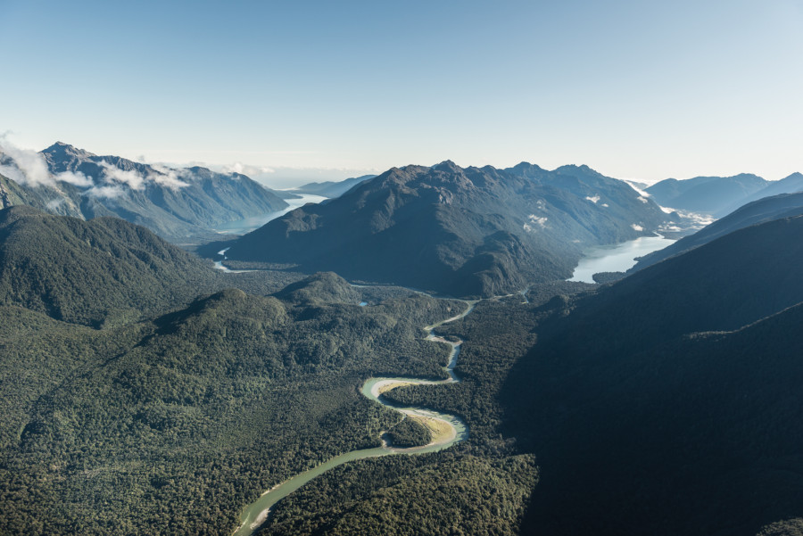 Winding river through native forest between mountain range